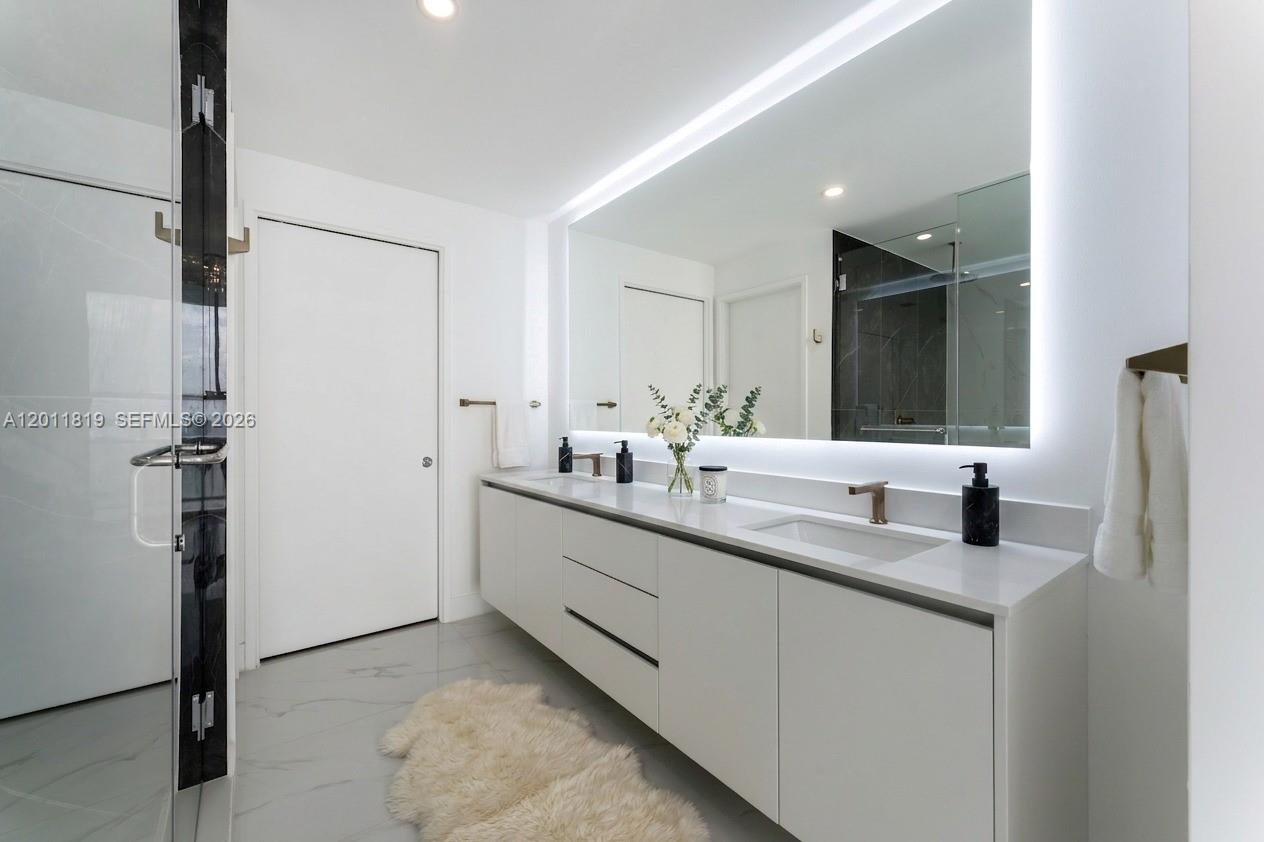 700 Northeast 24th Street, Unit 2504 Miami, FL 33137 - Photo 4 of 52 Spa-inspired primary bathroom featuring dual vanities, a deep soaking tub, a frameless glass rainfall shower, and designer porcelain tile throughout.