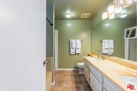 a bathroom with a granite countertop sink a large mirror and a bathtub