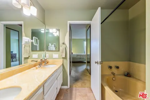 a spacious bathroom with a tub sink and mirror