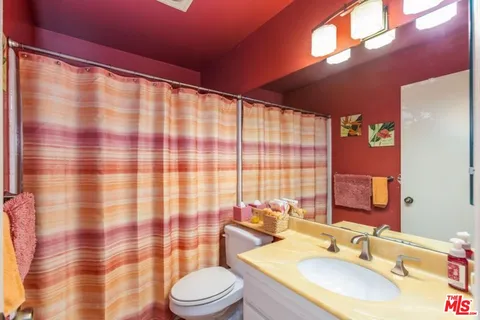 a bathroom with a sink a toilet a mirror and shower curtain