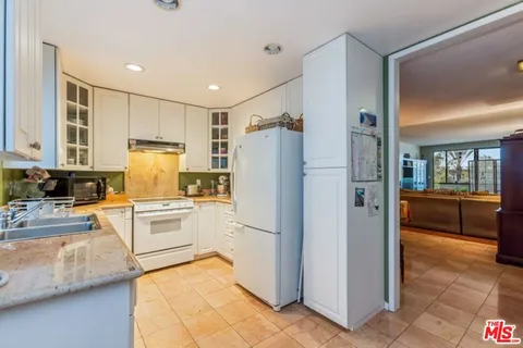 a kitchen with a refrigerator a stove top oven and cabinets