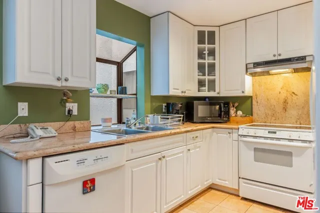 a kitchen with granite countertop white cabinets and white appliances