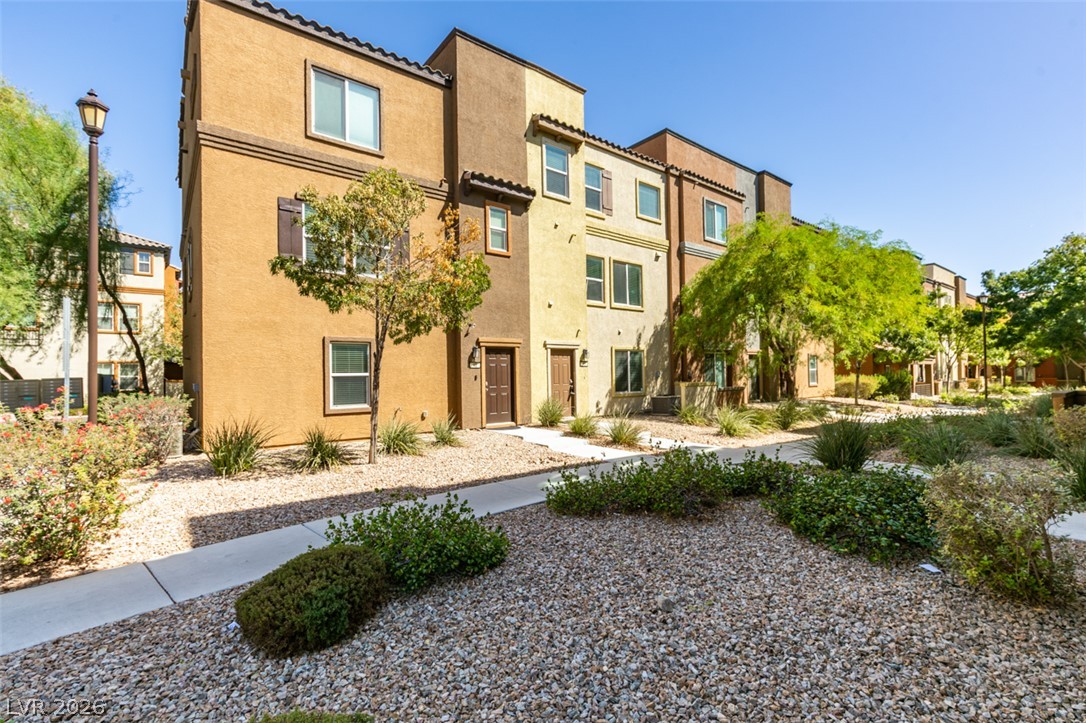 4650 Ranch House Road, Unit 46 North Las Vegas, NV 89031 - Photo 2 of 38 Multi-level townhomes showcase warm stucco exteriors framed by low-maintenance desert landscaping and concrete walkways.