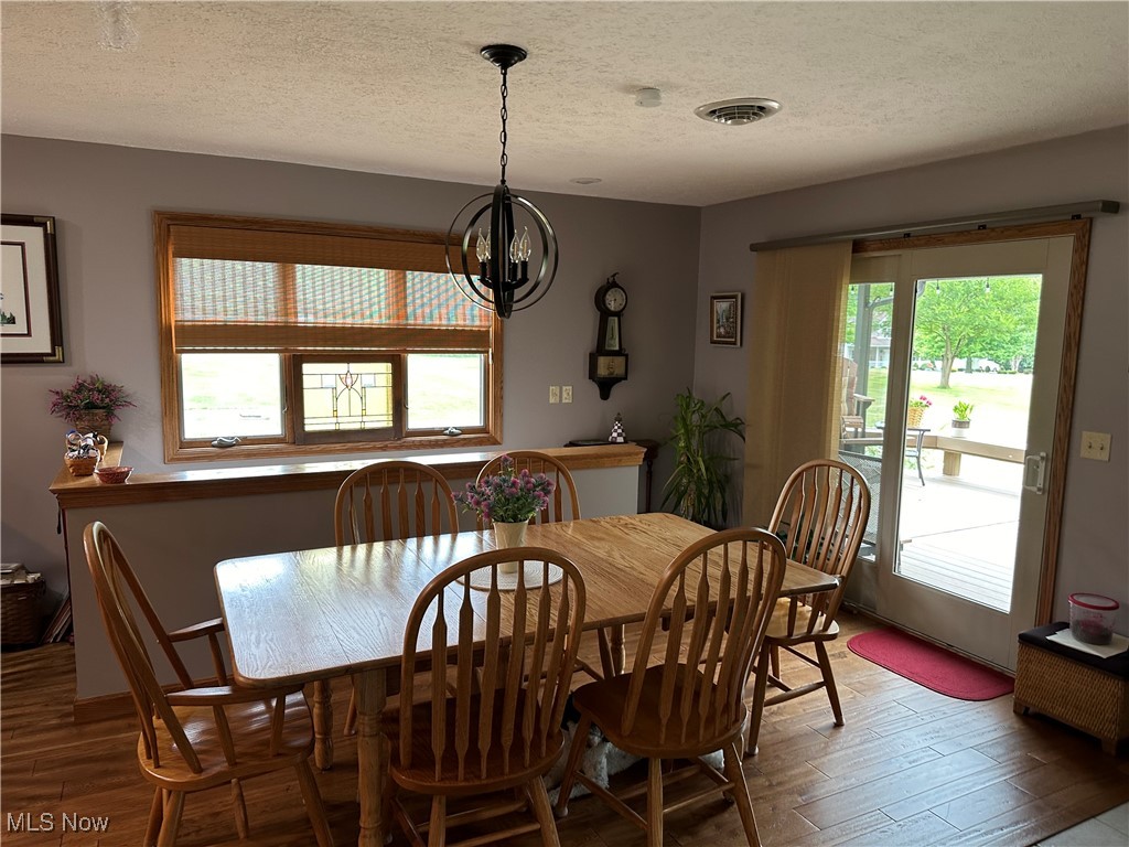354 Big Bass Road Willard, OH 44890 - Photo 14 of 29 Dining area with a notable chandelier, wood-type flooring, a healthy amount of sunlight, and a textured ceiling