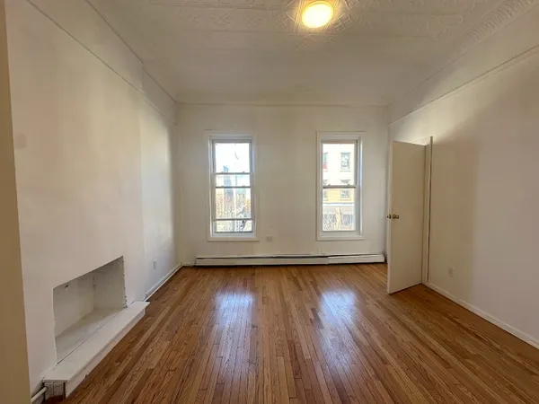 a view of an empty room with wooden floor and window
