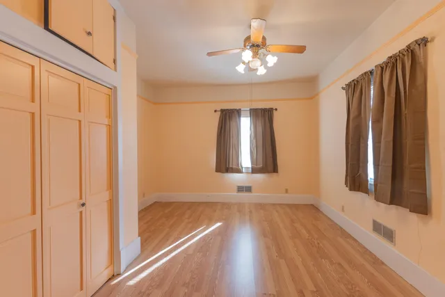 a view of an empty room with a window and wooden floor
