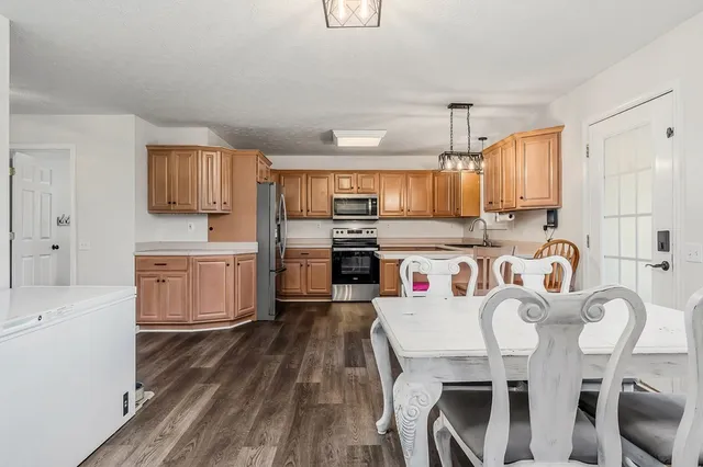 a kitchen with stainless steel appliances granite countertop a microwave a stove a sink dishwasher a dining table and chairs with wooden floor