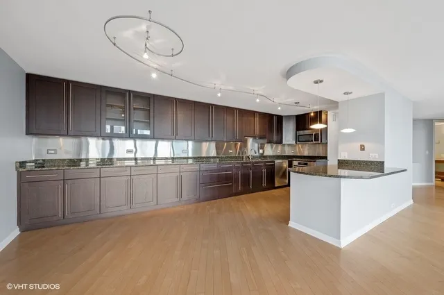 a large kitchen with stainless steel appliances granite countertop a stove a sink and a microwave