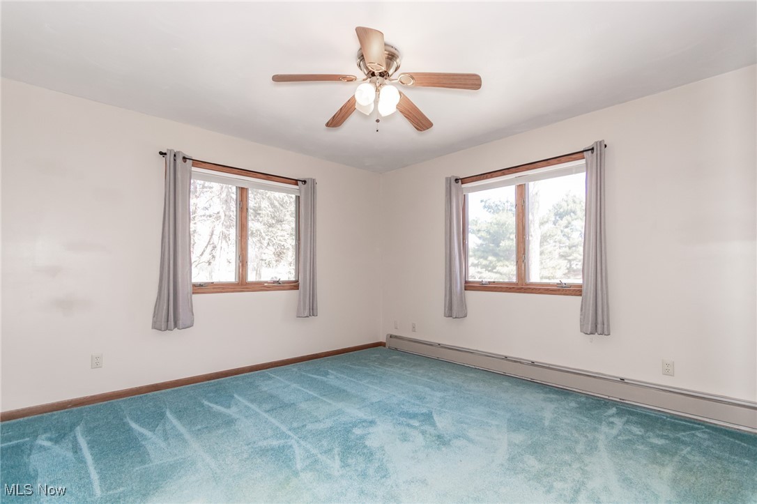 2866 South County Line Road Madison, OH 44057 - Photo 32 of 48 Empty room with baseboards, ceiling fan, a baseboard heating unit, and carpet flooring