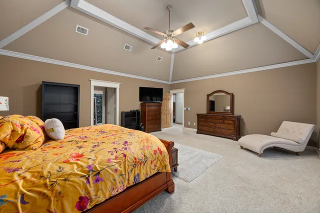 a spacious bedroom with a large bed and a chandelier
