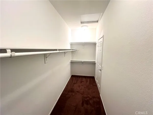 a walk in closet with wooden floor