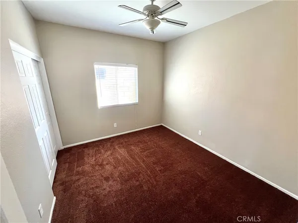an empty room with a window and a fan