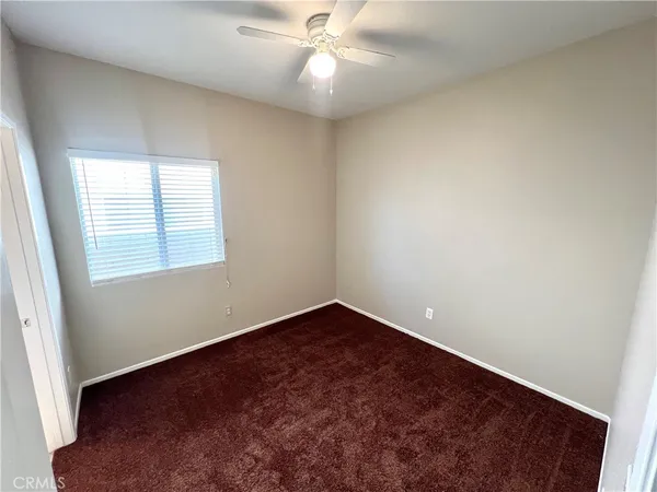an empty room with a window and a fan