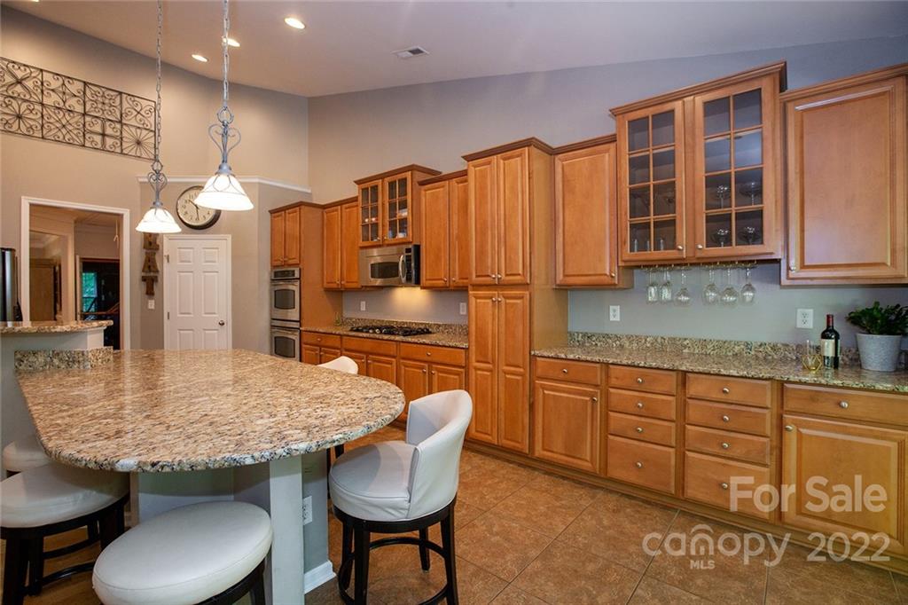 1292 Valhalla Drive Denver, NC 28037 - Photo 13 of 47 a kitchen with granite countertop a table chairs stove and cabinets