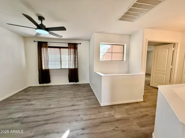 a view of empty room with wooden floor and fan