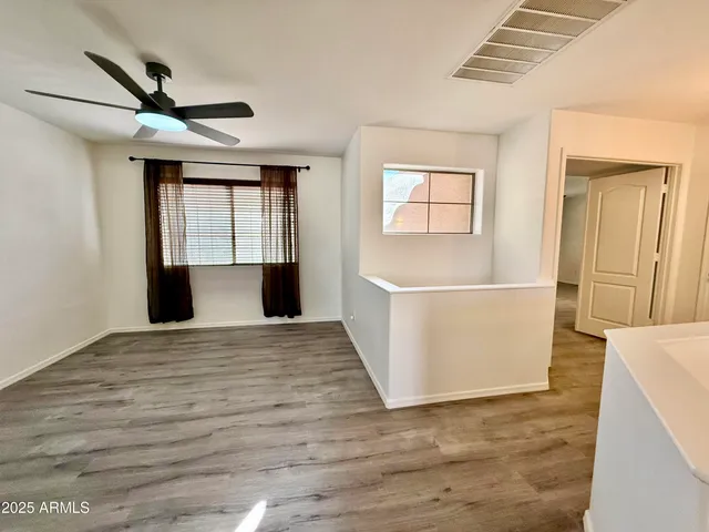 a view of empty room with wooden floor and fan