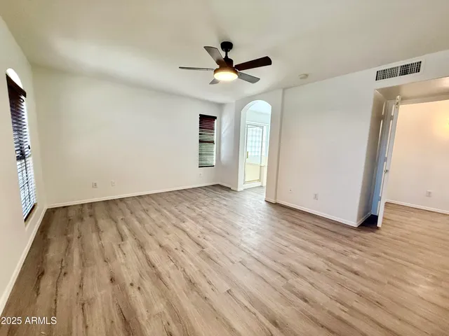 a view of empty room with wooden floor and fan