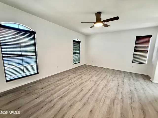 a view of empty room with wooden floor and fan