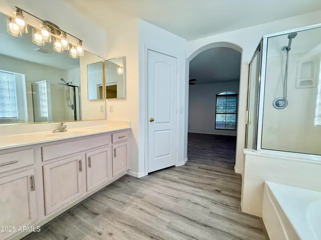 a spacious bathroom with a double vanity sink a large mirror and shower