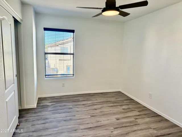 an empty room with wooden floor cabinet and windows