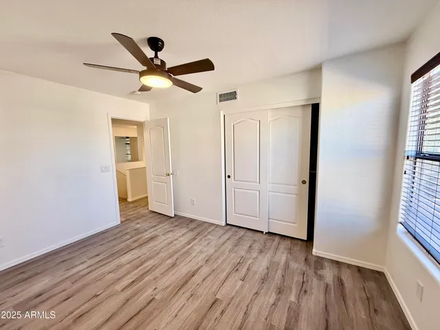 a view of empty room with wooden floor and fan