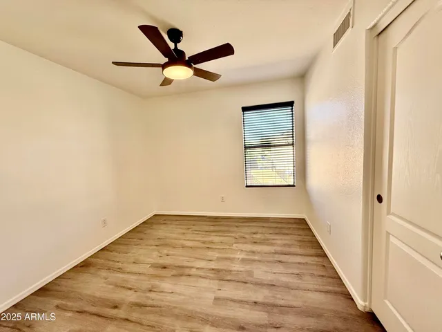 an empty room with wooden floor fan and windows