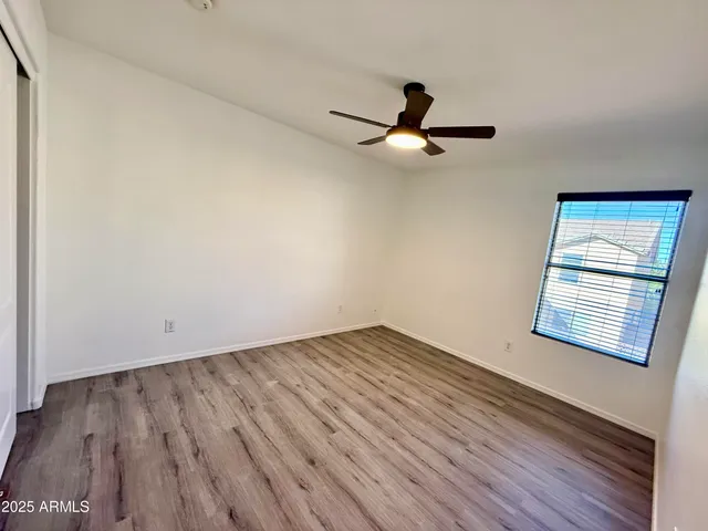 an empty room with wooden floor fan and windows