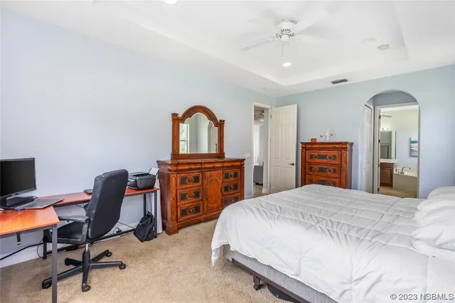 a bedroom with a bed a computer on the desk and chair