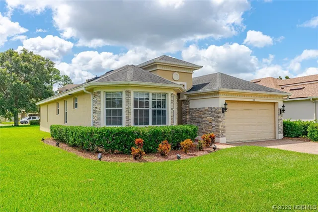 a front view of a house with a yard and potted plants