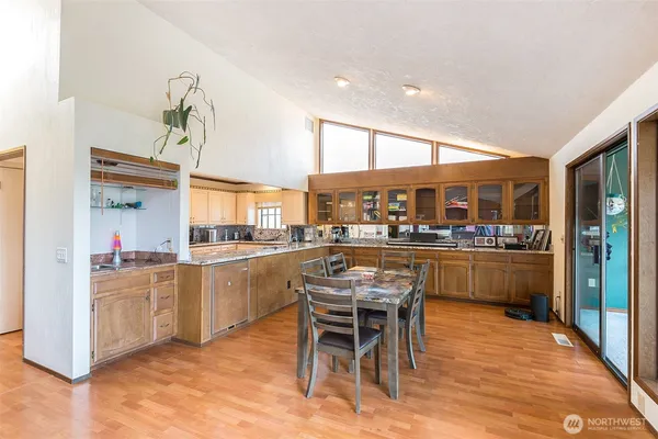a kitchen with stainless steel appliances kitchen island granite countertop a table chairs sink and cabinets
