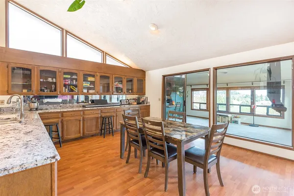 a dining hall with stainless steel appliances granite countertop a dining table and chairs with wooden floor