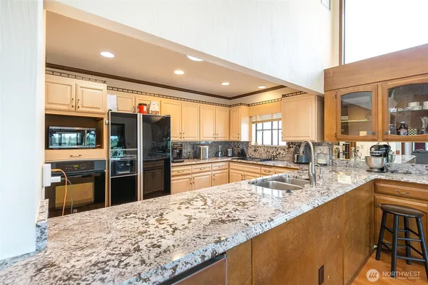 a large kitchen with stainless steel appliances granite countertop a large counter top and a refrigerator