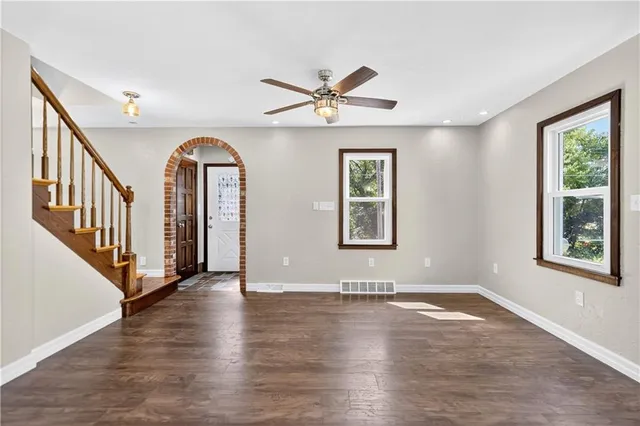 an empty room with wooden floor chandelier and windows