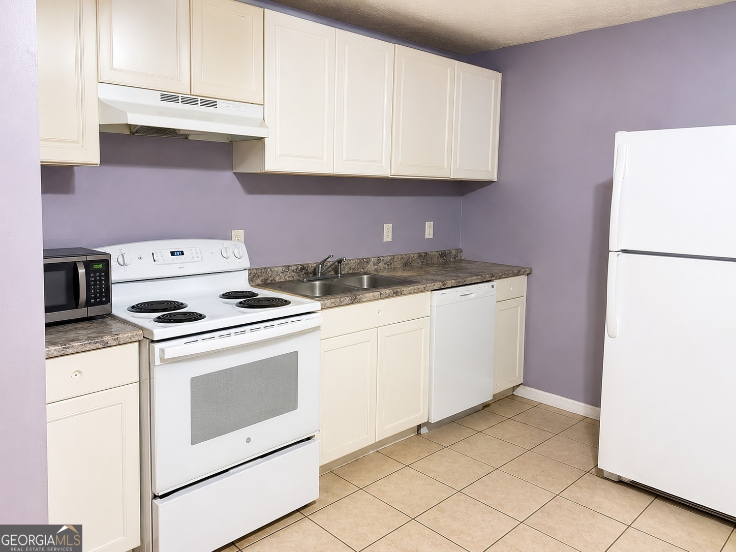 7055 Swift Street Lithonia, GA 30058 - Photo 4 of 9 a kitchen with granite countertop white cabinets and white appliances