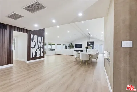 a view of a living room a dining room wooden floor and a ceiling fan