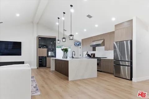 a kitchen with stainless steel appliances kitchen island granite countertop a refrigerator a stove a microwave oven a sink with island and chairs