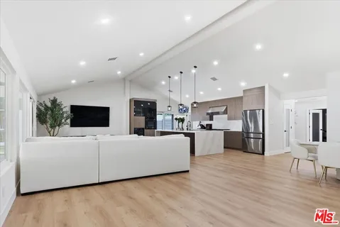 a living room with furniture a flat screen tv and kitchen view
