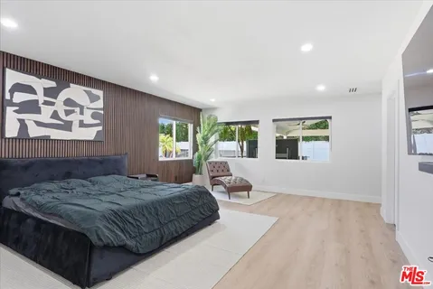 a bedroom with a large bed couch and windows