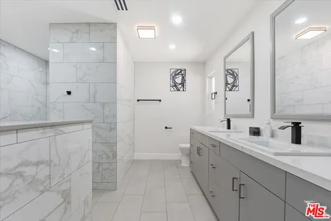 a spacious bathroom with a granite countertop sink a mirror and a shower