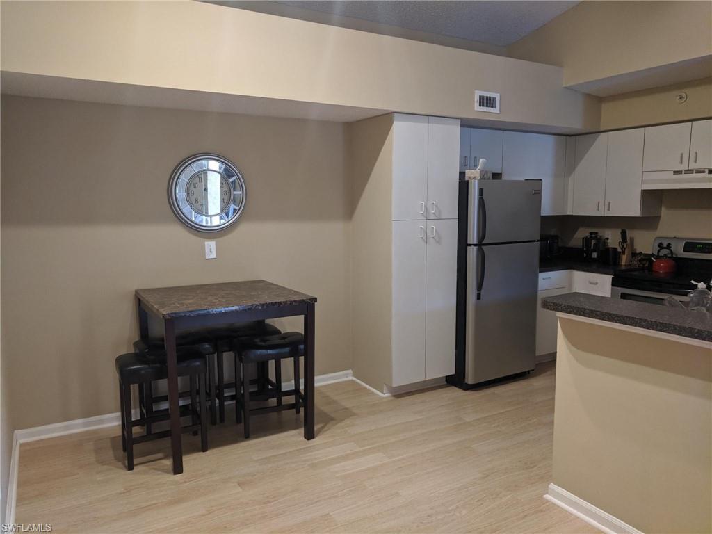 13521 Eagle Ridge Drive, Unit 121 Fort Myers, FL 33912 - Photo 3 of 12 a kitchen with a refrigerator a stove and a chair