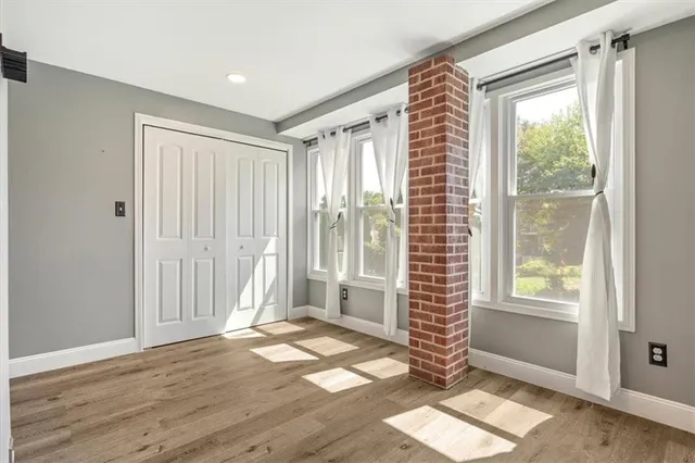 a view of an empty room with a window and wooden floor