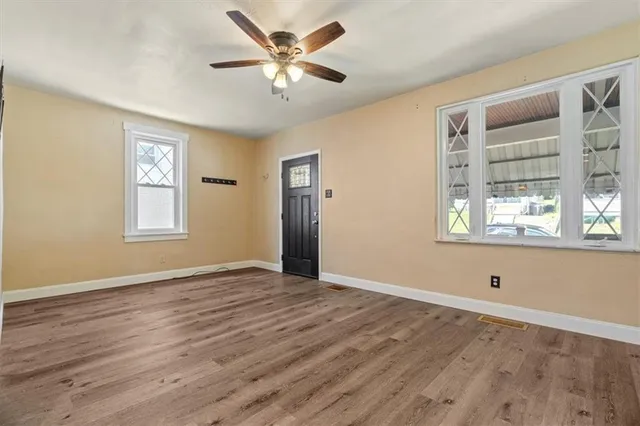 a view of an empty room with wooden floor and a window