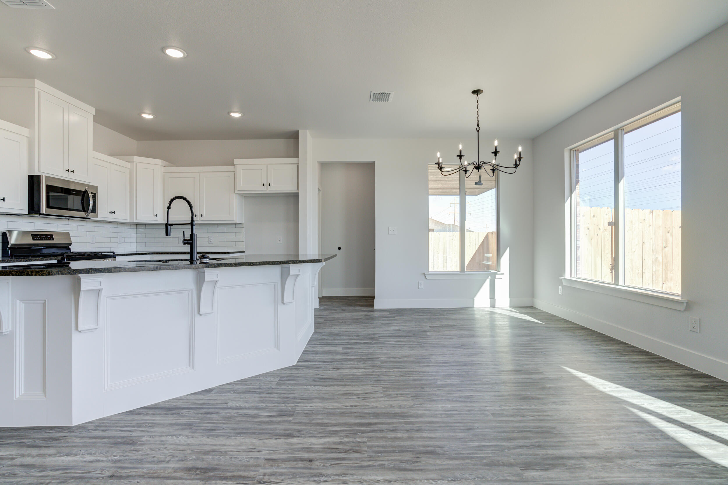 6926 12th Street Lubbock, TX 79416 - Photo 12 of 39 a kitchen with granite countertop a stove a sink a refrigerator and white cabinets with wooden floor