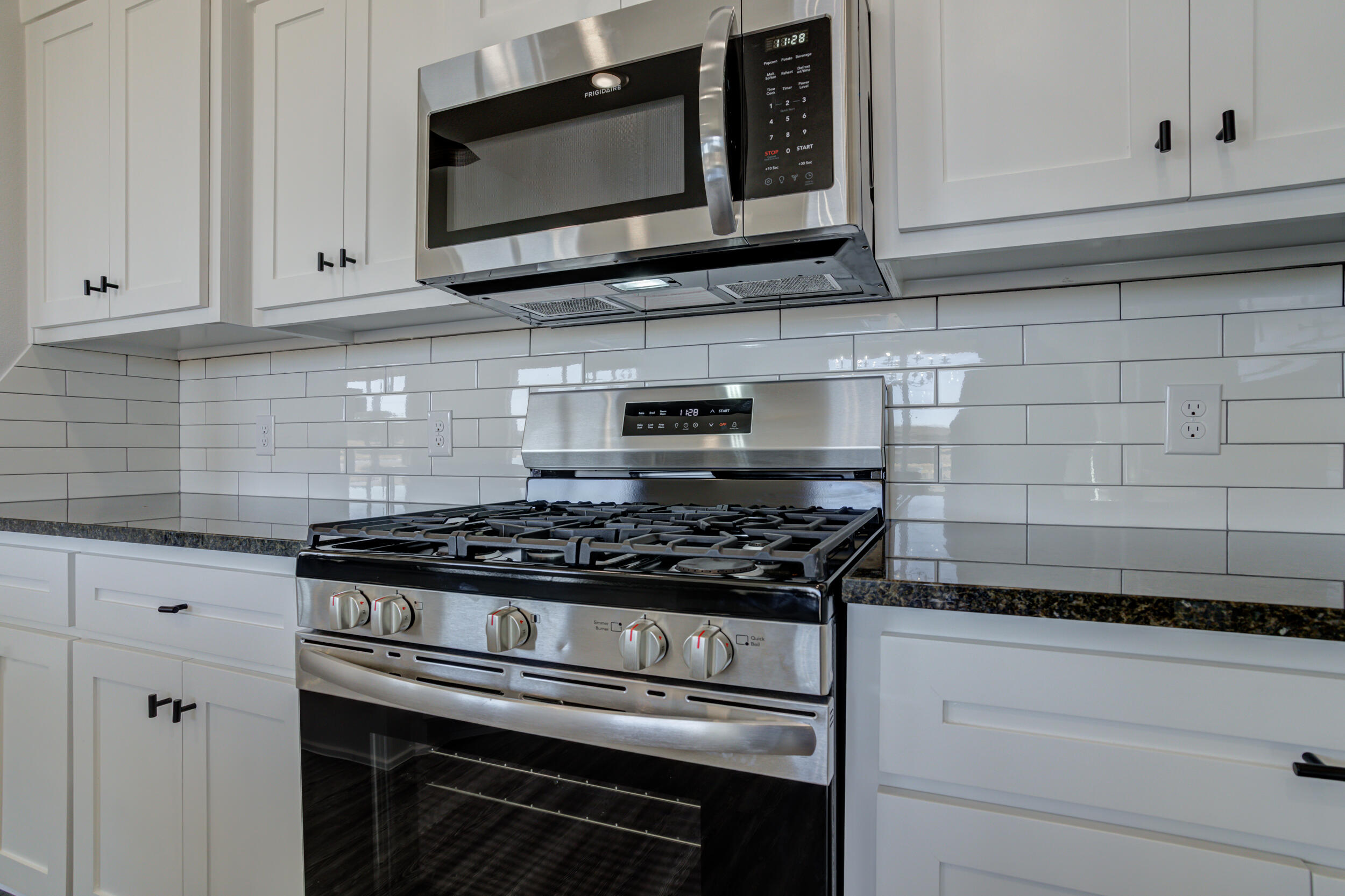 6926 12th Street Lubbock, TX 79416 - Photo 17 of 39 a kitchen with stainless steel appliances granite countertop white cabinets and a stove top oven