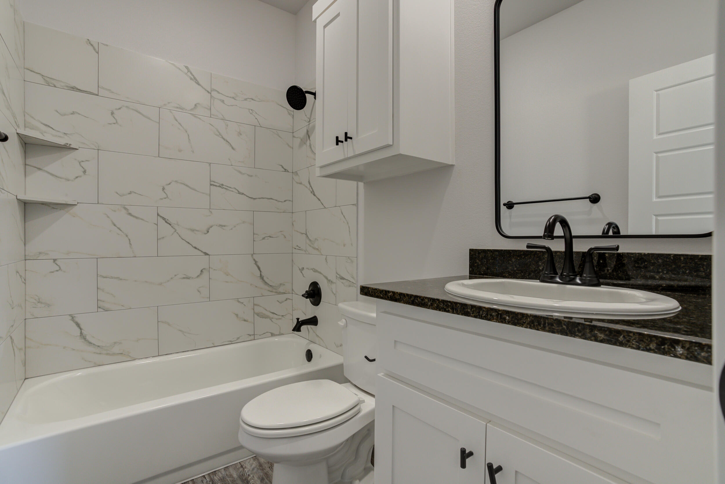6926 12th Street Lubbock, TX 79416 - Photo 32 of 39 a bathroom with a granite countertop toilet a sink and bathtub