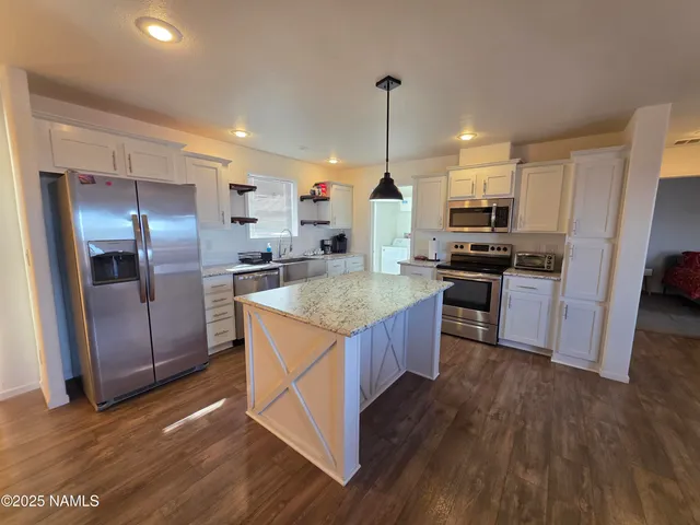 a kitchen with stainless steel appliances granite countertop a stove a sink dishwasher a refrigerator and a wooden floor