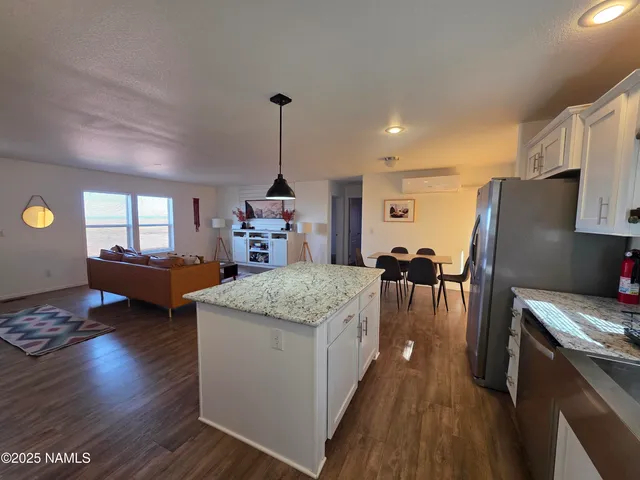 a kitchen with stainless steel appliances granite countertop a refrigerator a stove and a wooden floors