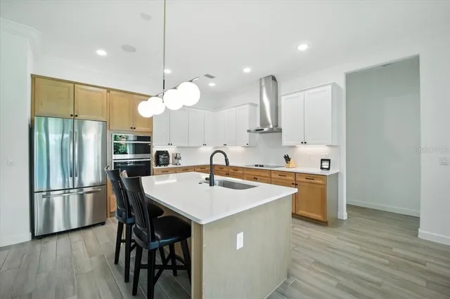 a kitchen with stainless steel appliances granite countertop a refrigerator a sink dishwasher a dining table and chairs with wooden floor