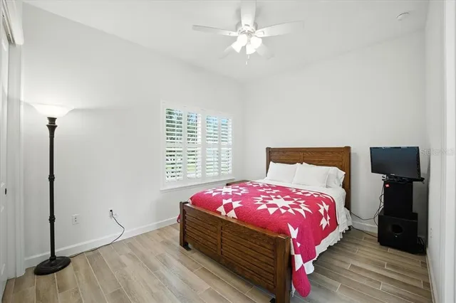 a bedroom with a bed and a large window with wooden floor