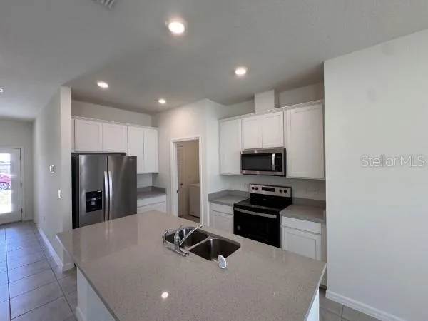 a kitchen with granite countertop a refrigerator and a stove top oven